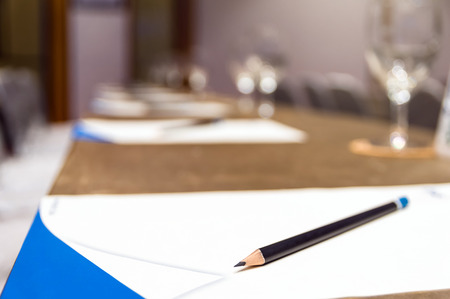 Pencil over the paper on the table of workplace with Glass of waterin the seminar or conference hall room, Business meeting conceptの写真素材