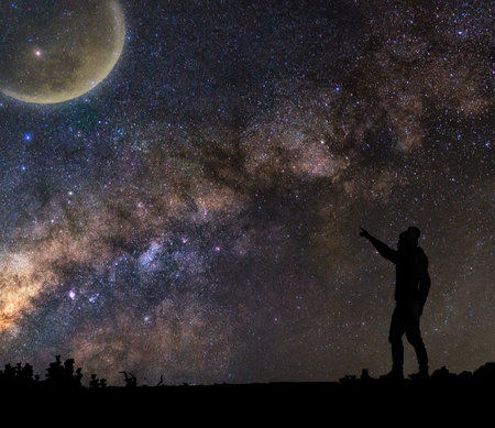 silhouette of a man who standing and pointing to the moon on milky way background