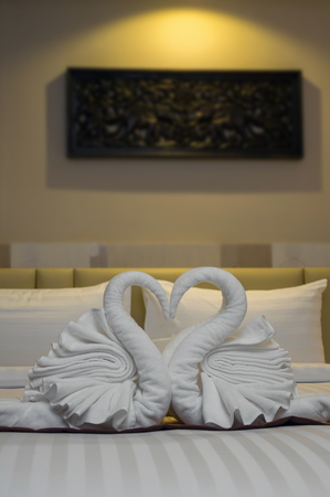 Close up two nice towels swans on the bedの写真素材