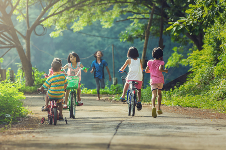 NAN, THAILAND - OCT 24 : A group of Asian Undefined happy children riding their bicycle on the street of countryside at BaanPaknai on October 24, 2016 in Nan province, Thailandのeditorial素材