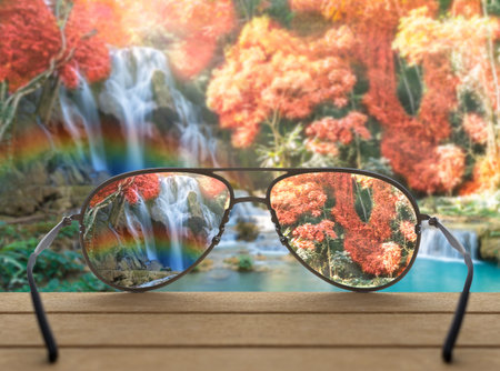 Conceptual image of waterfall focused in glasses lenses over the photo blurred of Beautiful...