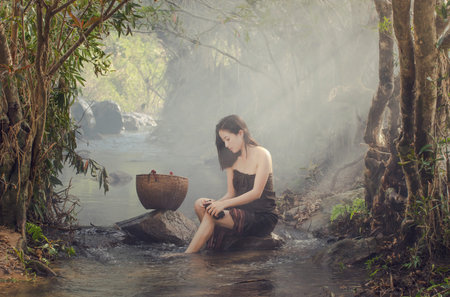 A beautiful Village women sitting and washing the clothes at the stream of waterfall or river, countryside and Folkways conceptの写真素材