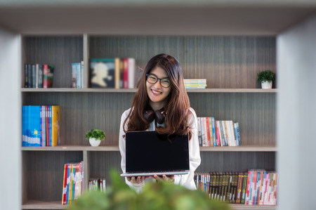 Portrait of smiling asian beautiful young businesswoman presentation by holding the laptop in the modern living room, lifestyle conceptの写真素材