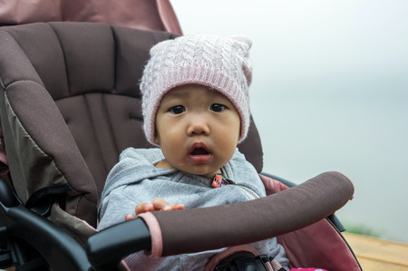 Portrait of happy asian baby child wearing the Sweater Dress on winter season in the Strollerの写真素材