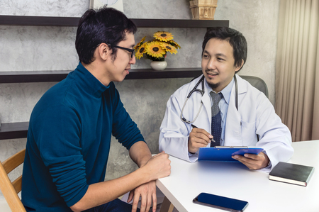 Asian male doctor discussing diagnosis with patient about his health in modern office of hospital, physician conceptの写真素材