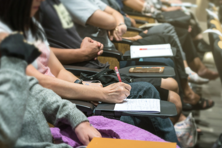 Close up shot of woman hand writing on the paper at the table in the conference hall or seminar meeting, business and education conceptの写真素材