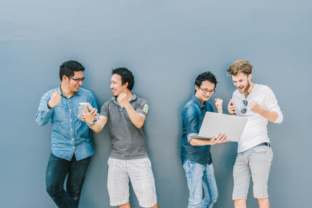 Group Of Asian and Multiethnic Business people with casual suit using each technology equipment with happy and celebrate action at the outdoor over the wall background, people business group conceptの写真素材