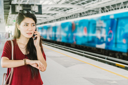 Asian woman passenger with casual suit using the social network via smart mobile phone in the Skytrain rails or subway for travel in the big city, lifestyle and transportation conceptの写真素材