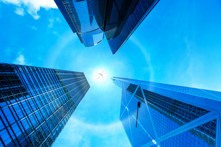 Modern business building glass of skyscrapers with sun carona and airplane, central Hong Kong, Business concept of architectureの写真素材