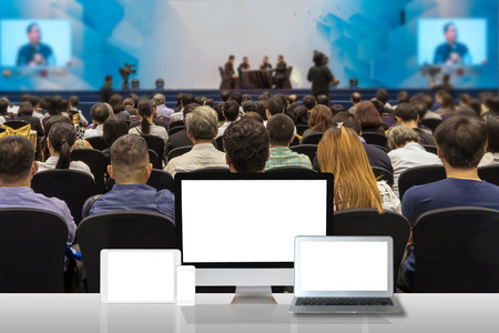 Computer set show on the white table over the Rear view of Audience in the conference hall or seminar meeting who Speakers on the stage, business technology and education conceptのeditorial素材