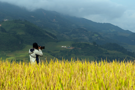 back side of photographer taking photo over the Rice fields on terraced of Mu Cang Chai District, YenBai province, Northwest Vietnamの写真素材