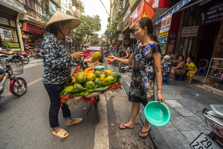 HANOI, VIETNAM - Sept 2017 : Undefined female trader traditional Street hawker selling fruits to vietnamese customer between walking in Hanoi. vietnam on september 24, 2017.のeditorial素材
