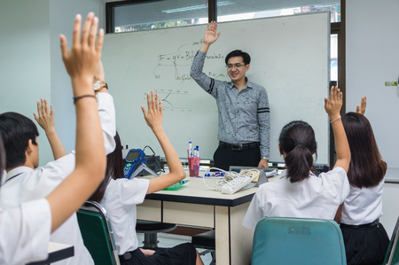 Asian teacher Giving Lesson over the the physics formular on white board in science laboratory classroom and students showing the hand for answer,school education concept,The teacher wrote himselfのeditorial素材