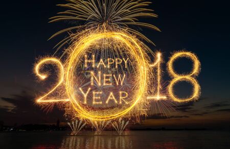 Happy new year 2018 written with Sparkle firework on fireworks with dark background, celebration and greeting cards conceptの写真素材