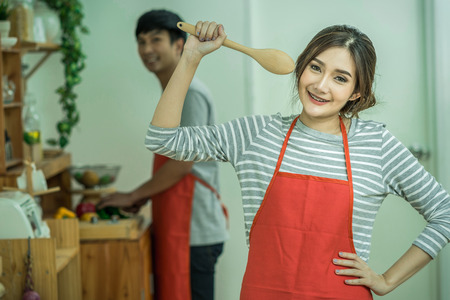 Portrait of Asian Lover or Couple cooking with smiling action in the kitchen room at the modern house, Couple and life style concept.の写真素材