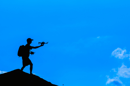 Silhouette of photographer with drone over the mountainの写真素材