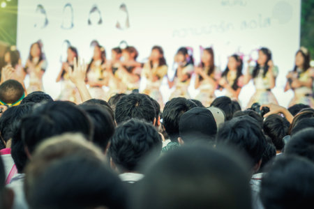 Rear side of Fan club people looking the girl group idol band during music entertainment public concert outdoor in evening time, Musical and concert conceptの写真素材