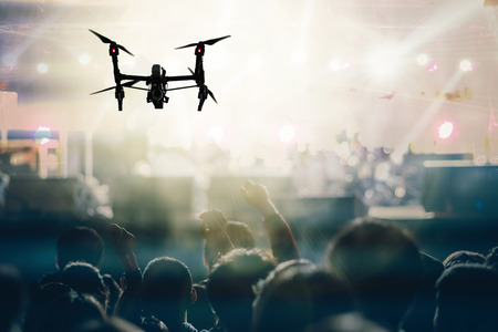 Closeup silhouette of Drone flying for taking video of Concert crowd and Music fanclub with show hand action which follow up the songer at the front of stage, musical and concert conceptの写真素材