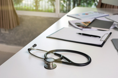 Stethoscope on the workplace table with some part of computer set and keyword with paper document office in the modern hospital or clinic, healthcare and physician conceptの写真素材
