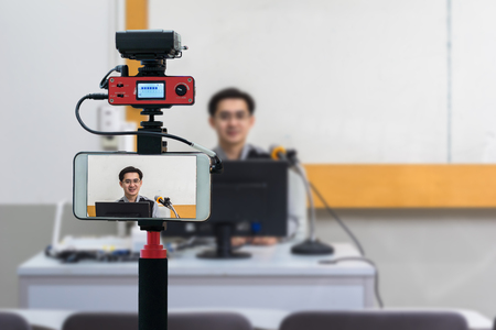 Closeup smart mobile phone taking Live of Asian teacher in the classroom,Camera for photographer or Video and Technology Live Streaming concept,University educationの写真素材