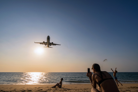 PHUKET, Thailand - FEB 5, 2018 : Undefined Travelers looking and talking photo to the Airplane landing closely at the sea beach beside the phuket international airport on Febuary 5, 2018, Thailand.のeditorial素材