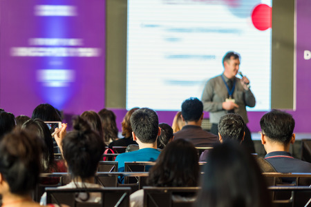 Rear view of Audience in the conference hall or seminar meeting which have speaker in front of the room on the stage, business and education concept