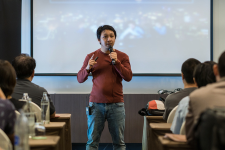 Asian Speaker with casual suit on the stage over the presentation screen in the business or education seminarの写真素材