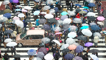TOKYO, JAPAN - OCTOBER 2017 : Undefined Japanese people crowd are walking to crosses the street with snow raining between the buildings of Shinjuku JR station on October 28, 2017 in Tokyo, Japan.のeditorial素材