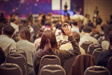 Speaker on the stage with Rear view of Audience in put hand up acton for question in the meeting or seminar meeting, business and education conceptの写真素材