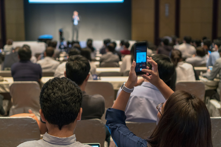 Closeup some attendee taking the photo the presentation in conference hall or seminar room backgroundの写真素材