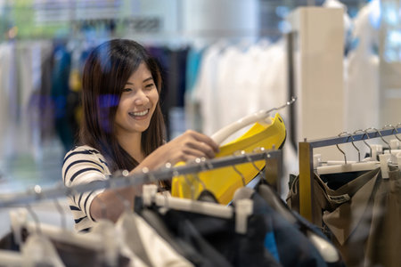 Happy Asian woman choosing clothes and skirt in glass store shop with happy action at department centerの写真素材