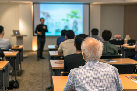 Rear side of Audiences sitting and listening the speackers on the stage in low light meeting room, event and seminar conceptの写真素材