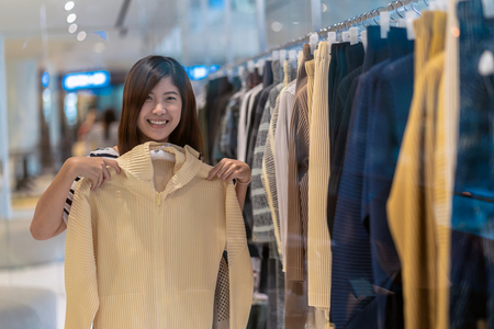 Happy Asian woman choosing clothes in store shop with happy action at department centerの写真素材
