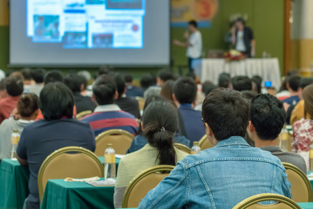 Rear view of Audience listening the speakers present the slide on the stage in the conference hall or seminar meeting, business and education conceptの写真素材