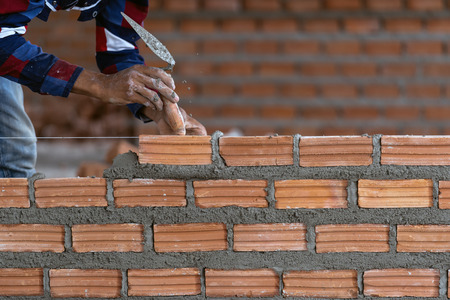 Closeup hand professional construction worker laying bricks in new industrial site. construct industry and masonry conceptの写真素材