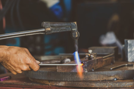 Closeup machinist hand bending the steel by torch  in metalworking factory, lathe grinding...