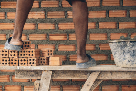Closeup leg of professional construction worker laying bricks in new industrial site. construct industry and masonry conceptの写真素材
