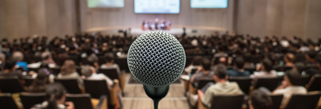 Banner and web page or cover template of Microphone over the Abstract blurred photo of conference hall or seminar room with attendee background, Business meeting conceptの写真素材