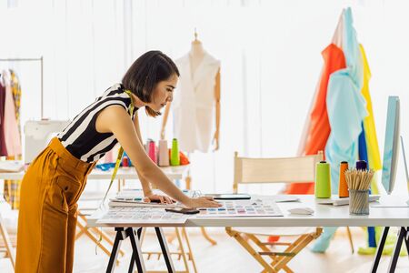 Young Asian designer woman working with computer and choosing multicolor chart at workplace, small business startup, Business owner entrepreneur, modern freelance job lifestyle concept.の写真素材