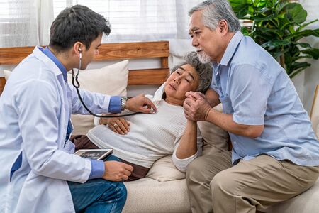 Closeup Doctor hand using stethoscope for auscultate Asian grandparent patient in house, service Life insurance at home, healthcare with Long live, Prevent epidemic and Covid19 Disease conceptの写真素材