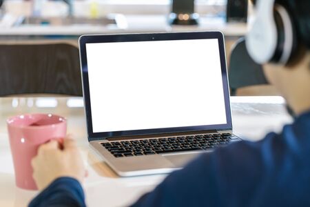 Back side of Asian business man wearing headphone and using laptop with white screen for creative and design in kitchen of house, working from home and stay at home when covid-19 outbreak,blank screenの写真素材