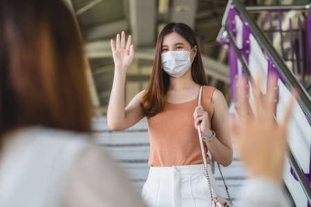 Young Asian woman passenger wearing surgical mask and listening music via smart mobile phone in subway train when traveling in big city at Covid19 outbreak, Infection and Pandemic conceptの写真素材