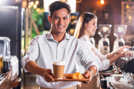 Asian Coffee shop owner serving bakery cake and coffee cup to customer in coffee shop, Small business owner and startup in coffee shop and restauran, waitress and barista conceptの写真素材