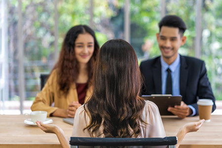 Back side of Young Asian woman graduate interviewing with two manager when discuss about her resume with poaitive motion in meeting room,Business Hiring new member conceptの写真素材