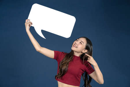 Happy young smiling woman holding copy space empty message bubbles on blueの写真素材