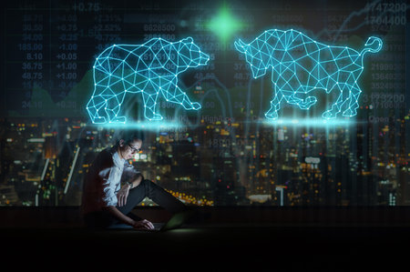 Asian businessman sitting and using the smart mobile phone showing bull and bear polygonal