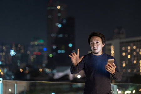 Asian creative freelancer using smart mobile phone with smile action in the financial district area at bangkok river side, Thailand, technology with career conceptの写真素材