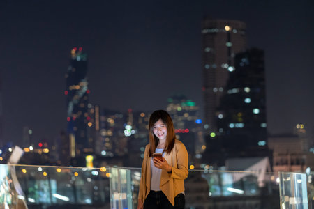 Asian businesswoman using smart mobile phone with smile action in the financial district area at...