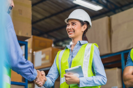 Manager of warehouse worker hand shake with assistant manager woman in local warehouse or factory, Asian and white caucasian people,Partner and colleague working together in success achievement conceptの写真素材