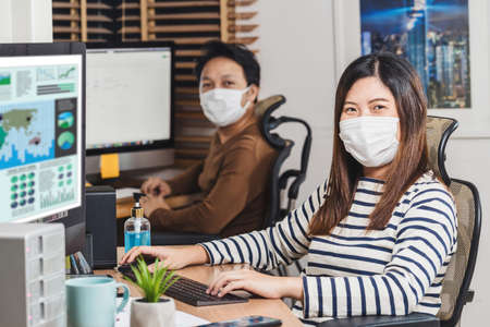 Portrait Couple of Asian colleagues wearing the surgical mask and working with computer in Home office when Covid-19 pandemic, Coronavirus outbreak,education and Social distancing,new normal conceptの写真素材